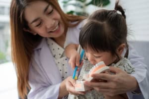 Dentist teaching child to brush teeth model