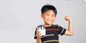 Smiling child holding milk, showing strength.