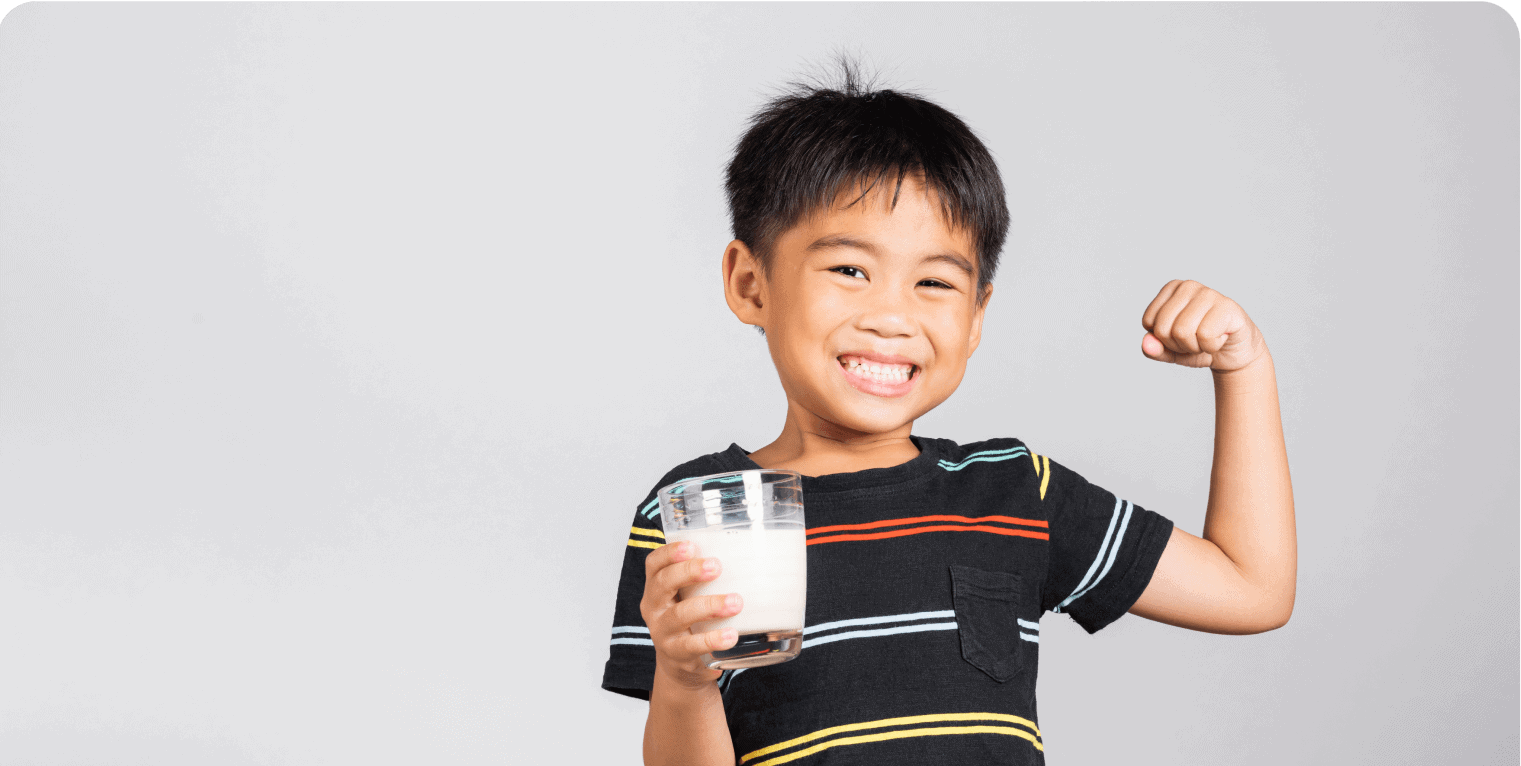Smiling child holding milk, showing strength.