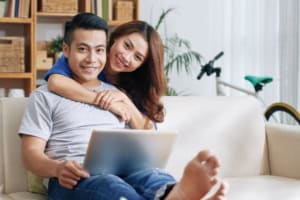 Couple smiling on sofa with a laptop