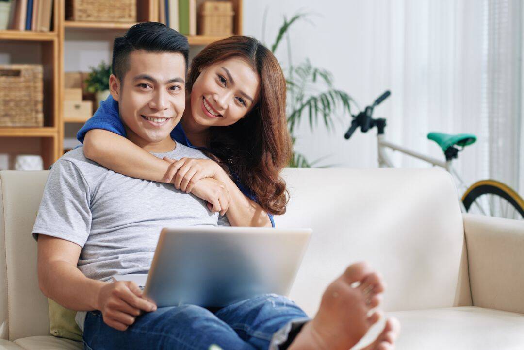 Couple smiling on sofa with a laptop