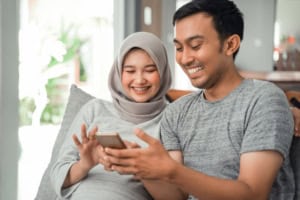 Smiling couple using smartphone at home