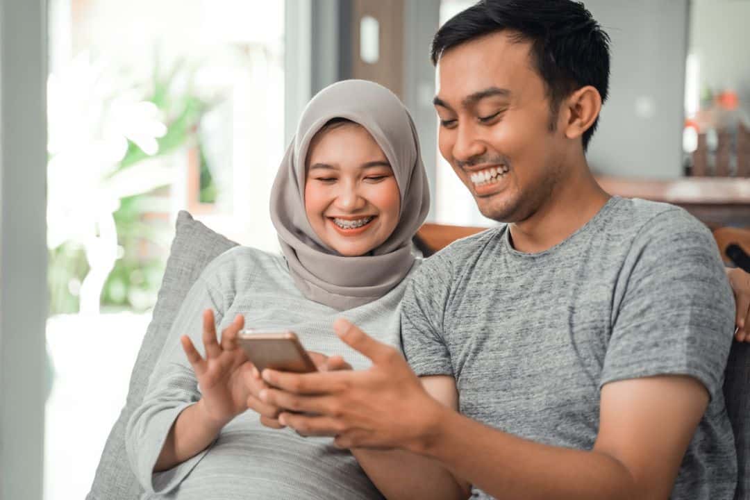 Smiling couple using smartphone at home
