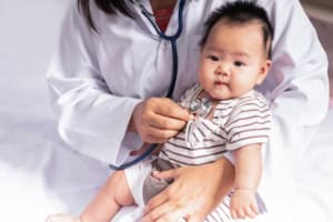 Doctor examining baby with stethoscope.