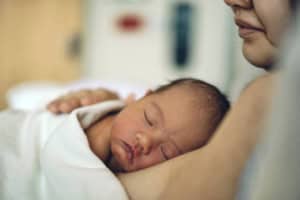 Baby sleeping on mother's shoulder, close-up of newborn care and maternal bonding.