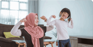 Mother and daughter flexing muscles, smiling at home.