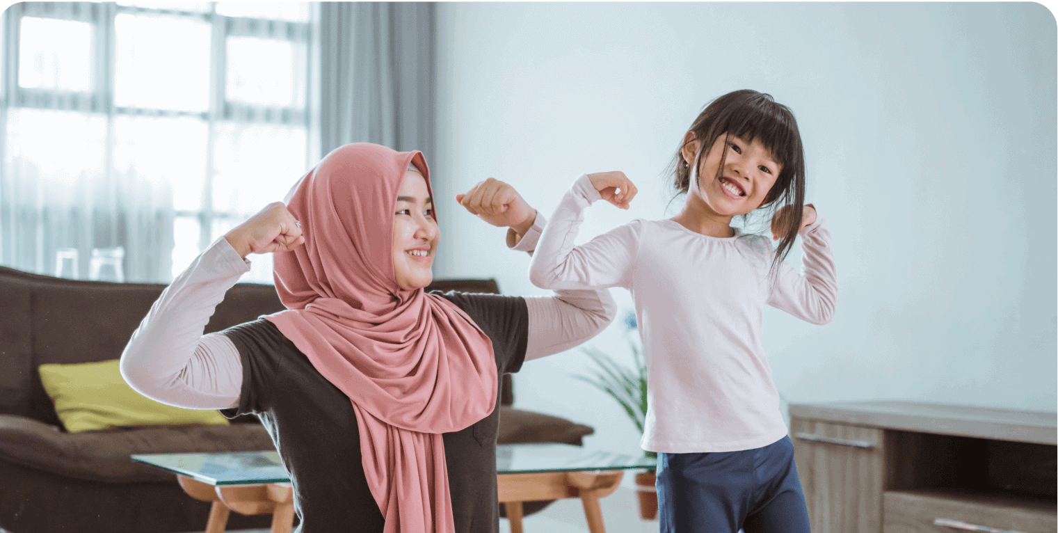 Mother and daughter flexing muscles, smiling at home.