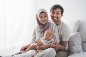 Smiling family with baby sitting on bed