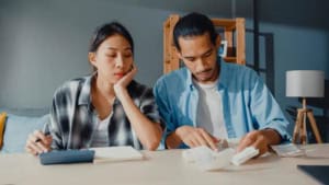 Couple calculating finances at home table.
